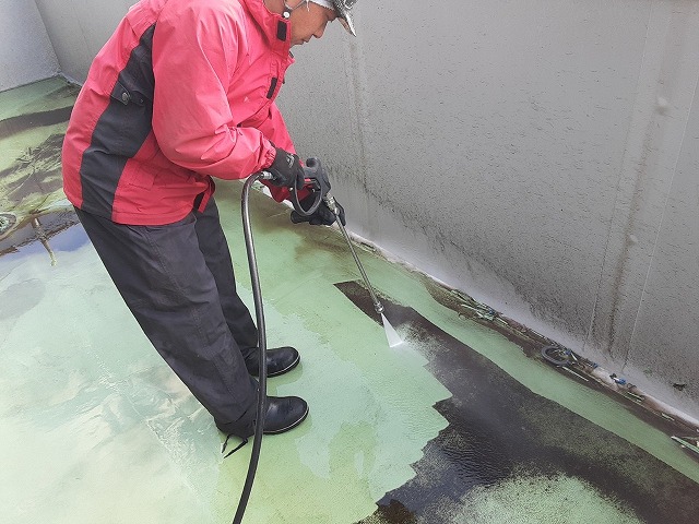 高圧洗浄でベランダの古い塗膜や苔などを洗い落としている状況