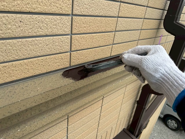 ハケを使い幕板の際部分に濃いブラウン色の塗料を塗布している様子