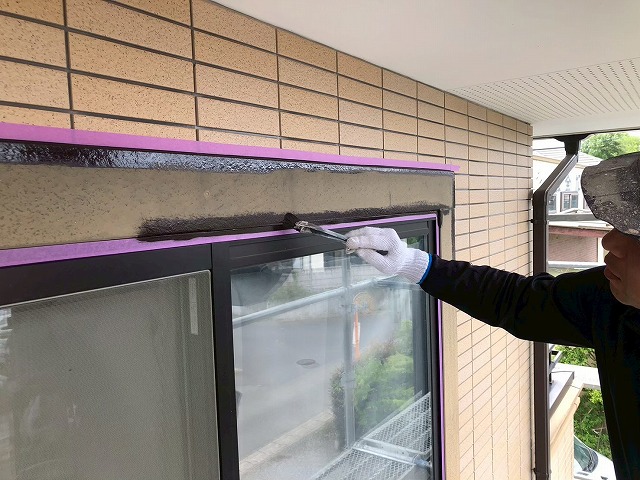 ハケで窓まわりモールに1回目塗装を行う作業員の様子