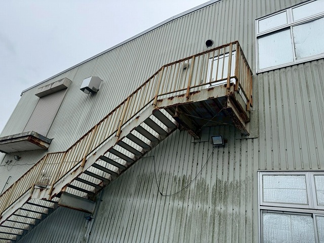 工場建物の鉄骨階段の手すり脚部のサビと塗膜剥がれ