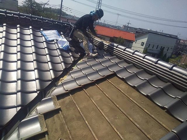 雨漏りの原因となっていた谷樋を交換するため、その周辺の瓦を取り外す作業員の様子