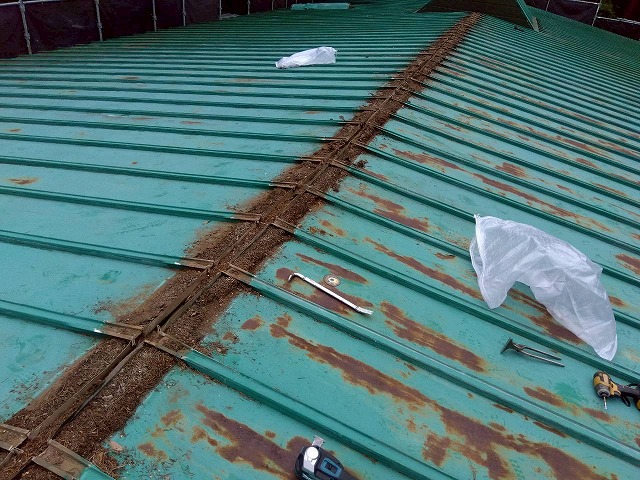 サビが広がる瓦棒葺き屋根の表面と解体用の道具が置かれた様子