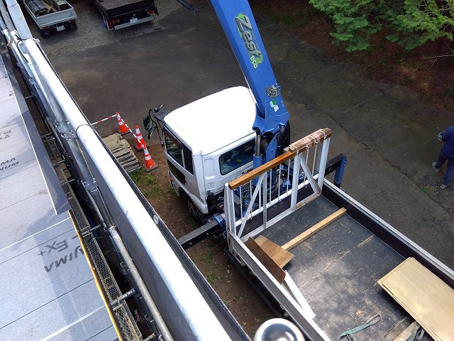 ユニック車を用いて金属屋根材を搬入する作業の様子