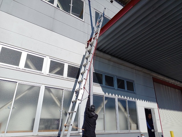 倉庫建物の雨樋清掃メンテナンスで下屋根部の清掃のためにはしごを設置