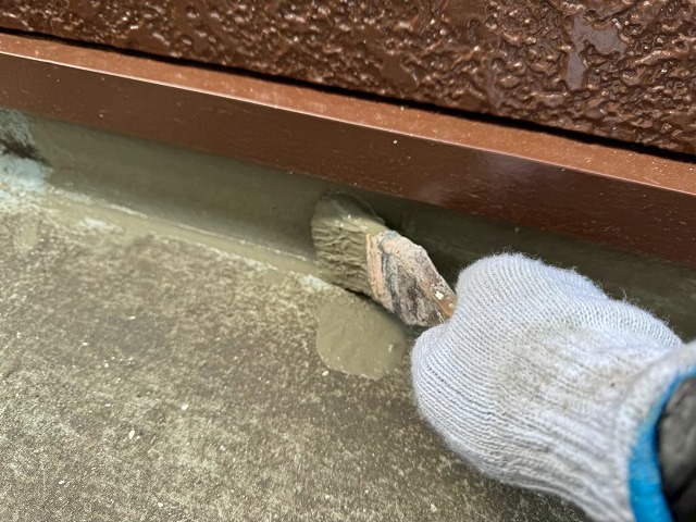 ベランダ防水修繕工事の立ち上がり部へのハケを用いた下地処理