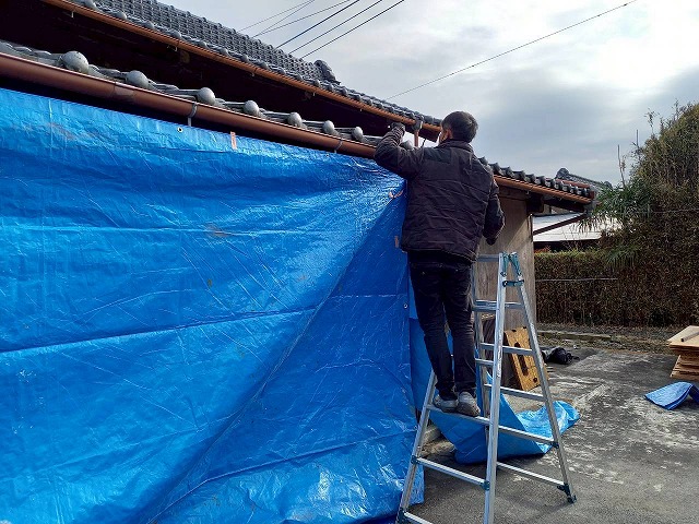 屋根葺き替え工事の前にブルーシートで養生を行っている様子