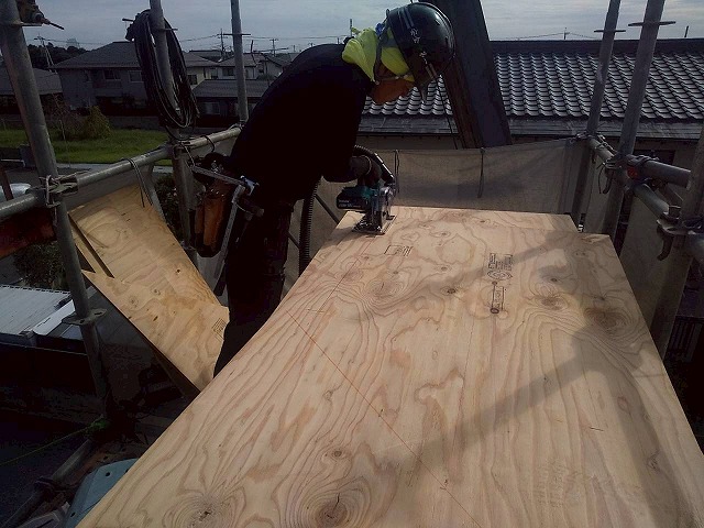 屋根葺き替え工事の野地板増し張り工程で構造用合板をカットしている様子