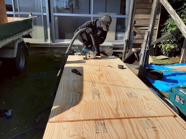 屋根葺き替え工事の野地板増し張り工程で構造用合板をカットしている状況