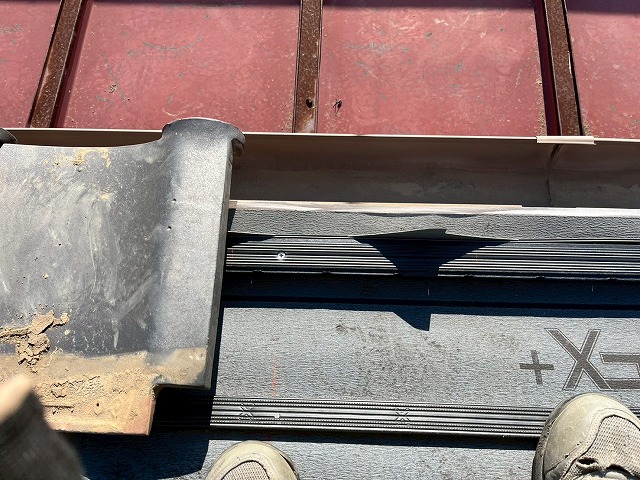 屋根葺き直し工事で軒先面戸へ被せるように軒瓦を設置している様子