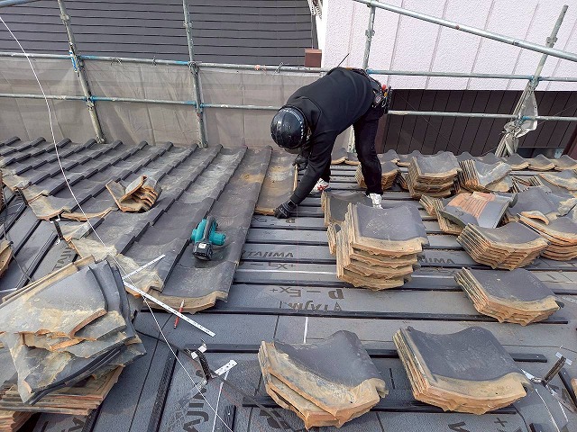 屋根葺き直し工事のと一度取り外した瓦を再設置している様子