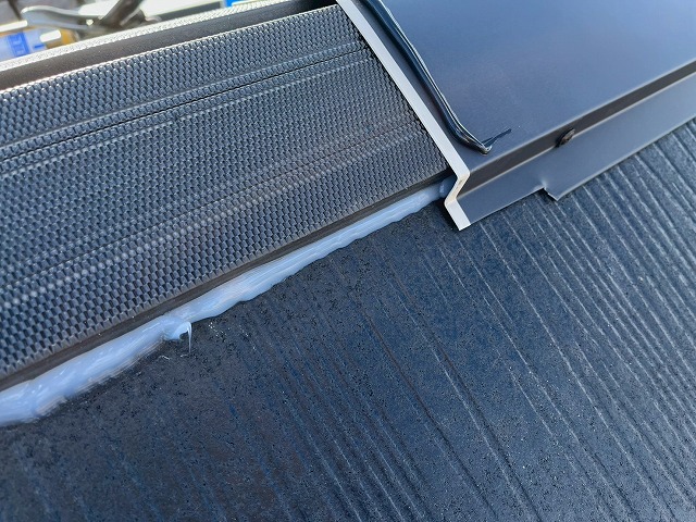 棟板金のジョイント部へ捨てコーキングを打設している状況