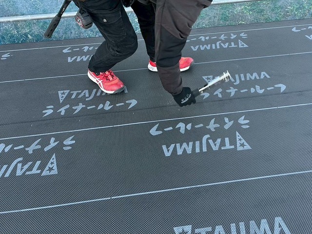 新築住宅屋根仕上げ工事で防水シートにタッカー留めを行う屋根職人