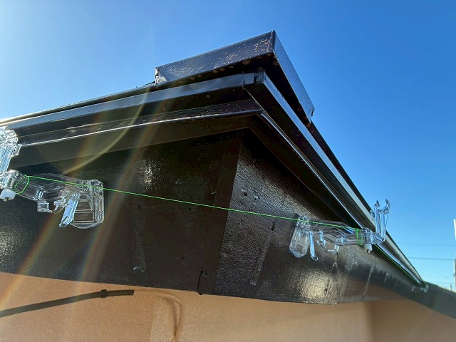 雨樋交換工事で水上と水下に水糸を張って軒樋吊具の勾配調整を行っている様子