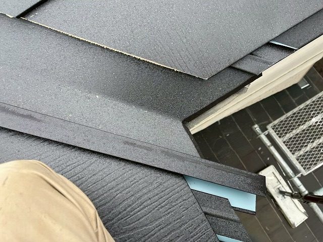 住宅屋根カバー工事で金属屋根本体へ谷止縁役物を差し込んでいる状況