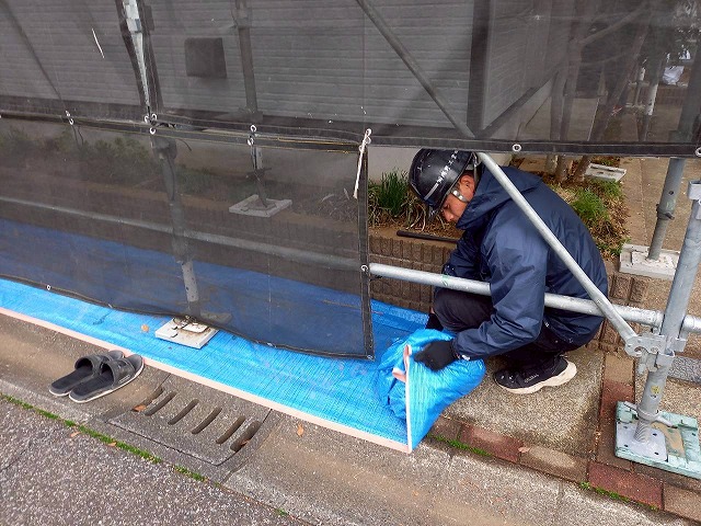 外壁塗装工事完了後に養生材を撤去しながら行っている現場清掃の様子