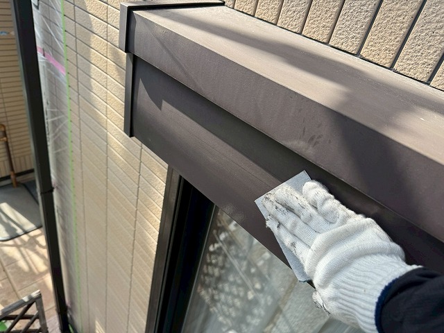 サンドペーパーでシャッターボックス表面のケレンを行う作業員