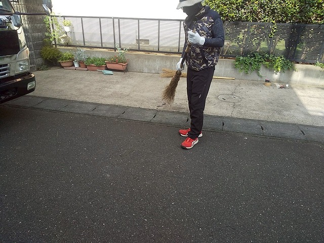 屋根カバー工事完了後に前面道路を清掃する屋根職人