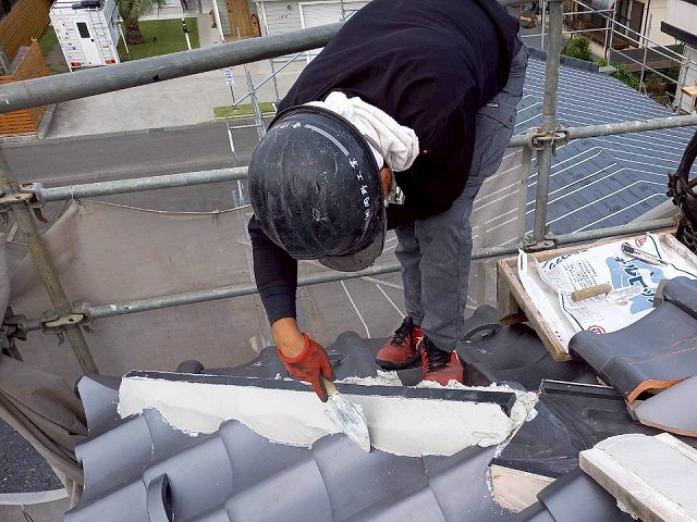 屋根葺き替え工事で隅棟部に漆喰材を塗り固めている様子