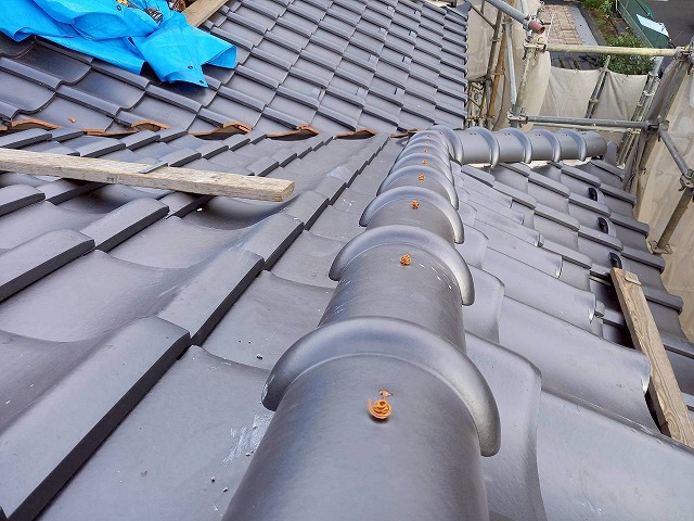 屋根葺き替え工事風切丸仕上げ工程の丸瓦へ通した銅線をくくり付けた状況