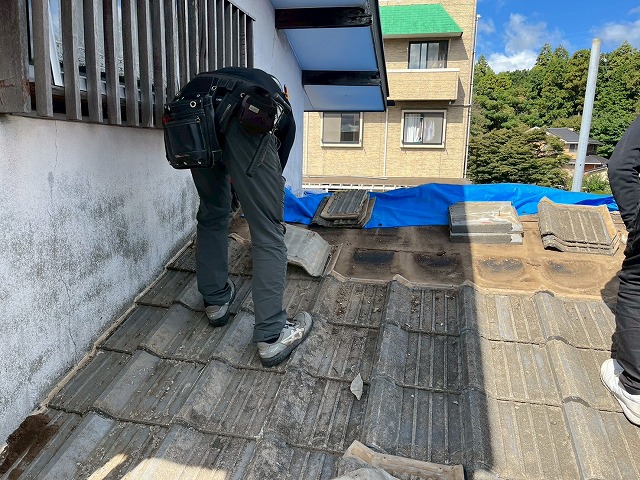 屋根葺き替え工事で既存セメント瓦を取り外している様子