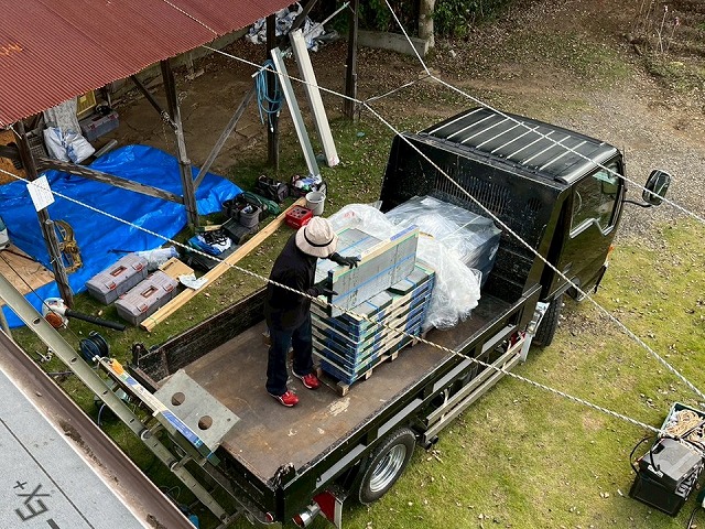 屋根葺き替え工事ではしご式の荷揚げ機で屋根仕上げ材を搬入している状況