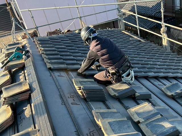 屋根葺き直し工事で瓦に釘を打ち込む屋根職人