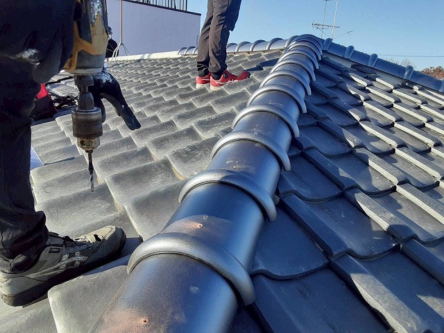 隅棟部へ設置する7寸丸瓦に下穴をあけている状況