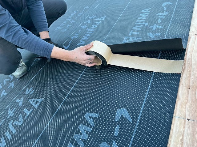 新築住宅屋根仕上げ工事の防水シートのジョイント部へ防水テープを貼り付け