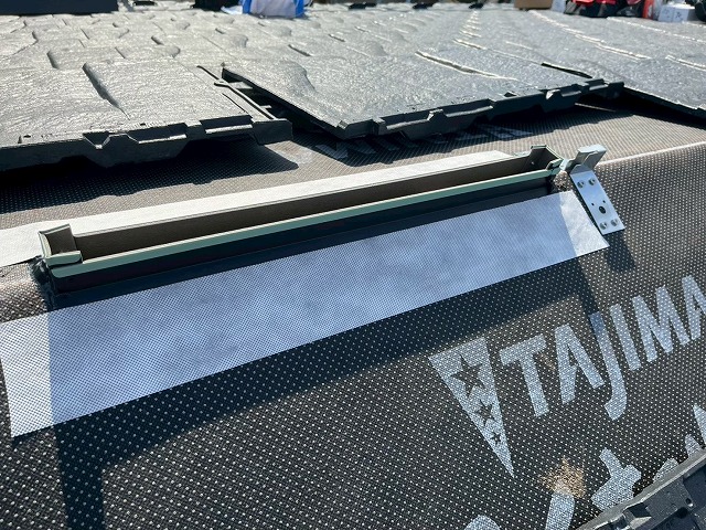 新築住宅屋根工事の棟部捨水切部材への防水テープ貼り付け