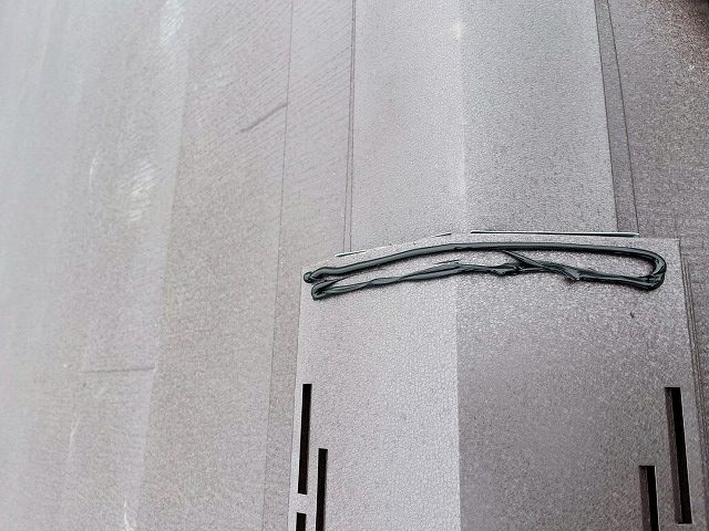 換気棟の端部に捨てコーキングを施して換気棟用エンドキャップをはめ込んでいる様子