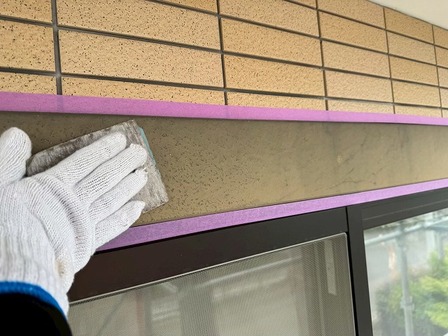 サンドペーパーで窓まわりモールの表面を下地処理する様子