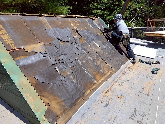 三角屋根の一面から金属屋根を撤去し、劣化した防水シートが露出した状態