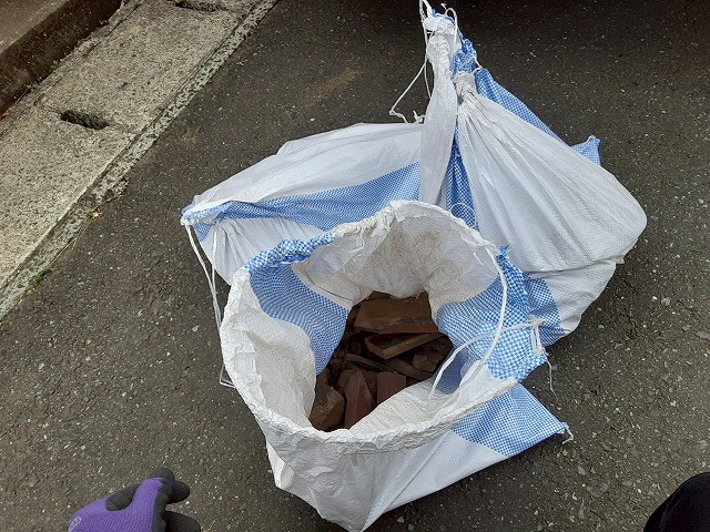 下屋根部棟取り直し工事で生じたガラをゴミ袋に詰め込んでいる様子