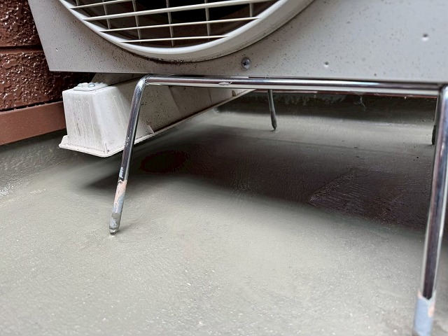 ベランダ防水修繕工事の下地処理のためにエアコン室外機を架台に載せて浮かせている状況