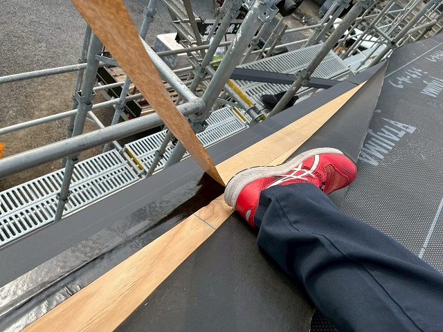 ルーがによる屋根仕上げ工事で軒先水切りに防水テープを貼り付けている様子