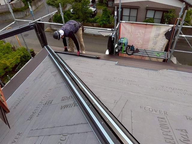 スーパーガルテクトを左から右へ順にジョイント部をはめ込みながら張り施工を進めている状況