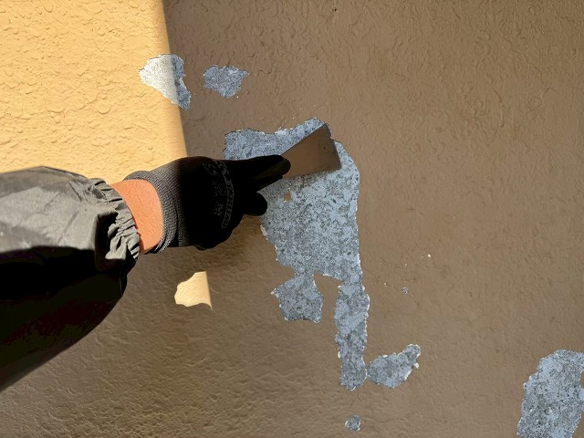 モルタル外壁塗装工事塗膜の浮き部分を剥がしている様子