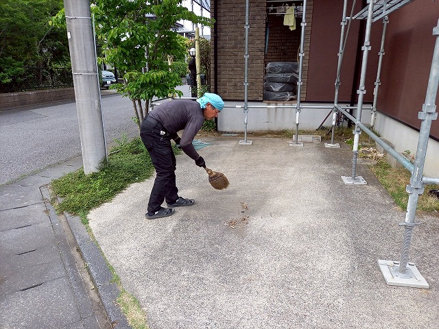 屋根カバー工事後に建物周囲を掃き掃除している状況
