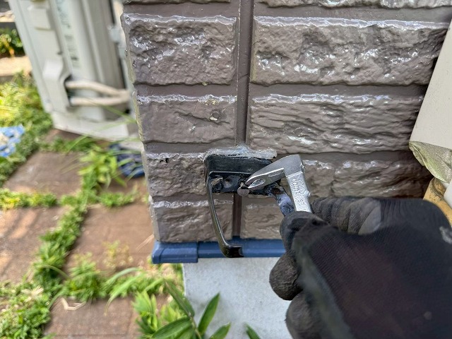 雨樋交換工事の竪樋の受け金具を取り外している様子