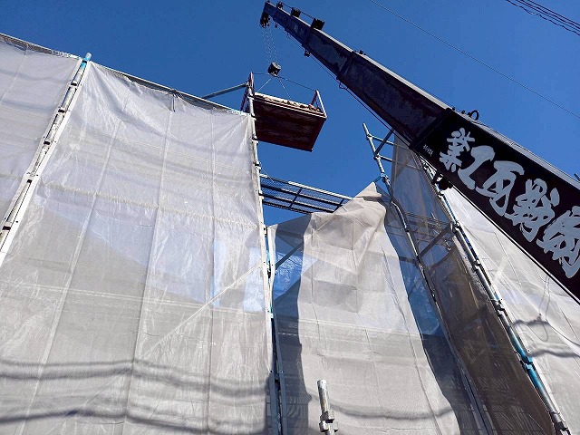 屋根葺き直し工事で解体した棟瓦をユニック車で降ろしている様子