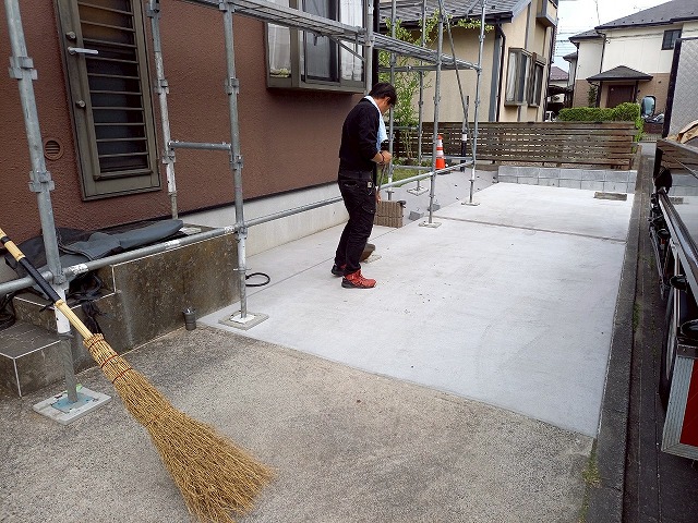 屋根カバー工事後に土間コンクリートをほうきで清掃している状況