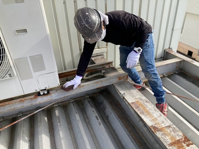 倉庫建物鉄骨塗装工事の研磨用たわしでケレンを行う塗装職人