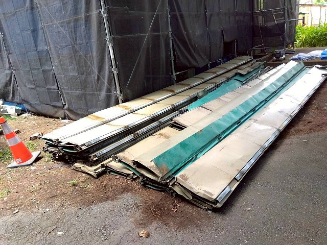 撤去され地面に並べて置かれた金属屋根材の様子