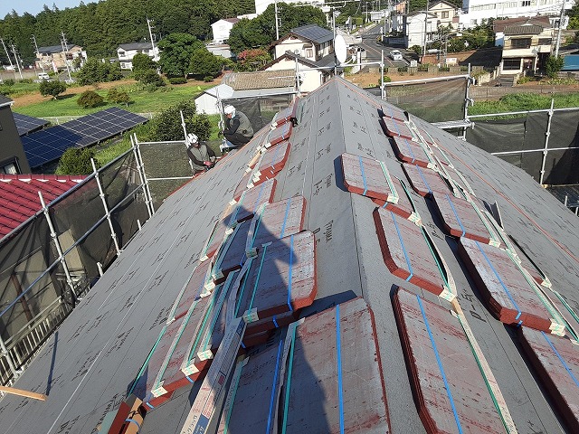 屋根に屋根材を上げる